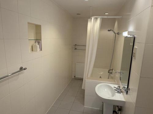 a white bathroom with a sink and a shower at The Cumberland Hotel in Eastbourne