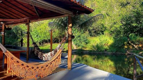a hammock on a deck next to a river at Chalés Riacho da Serra Capitólio in Guapé
