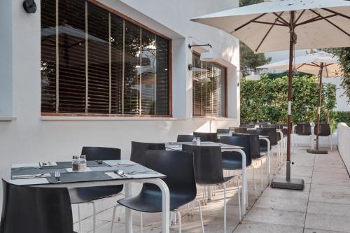 a restaurant with tables and chairs and an umbrella at Prinsotel Alba & Spa in Cala d´Or