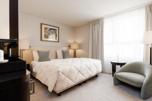 a bedroom with a bed and a chair and a window at Grand Hotel Casselbergh in Bruges