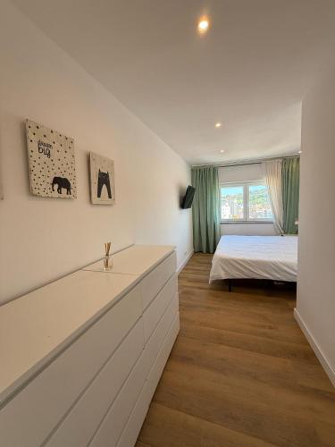 a white bedroom with a bed and a window at Front Beach Costa Caparica Lisbon in Costa da Caparica