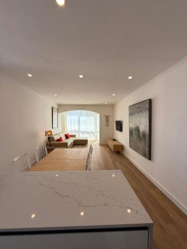 a living room with white walls and a large table at Front Beach Costa Caparica Lisbon in Costa da Caparica