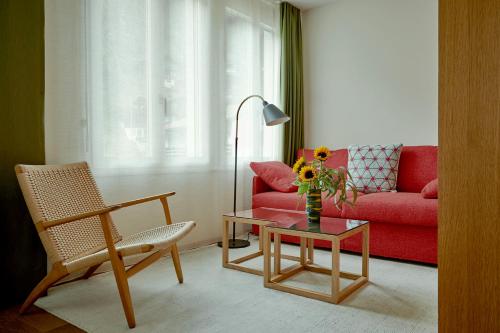 a living room with a red couch and a table at Bellevue Parkhotel & Spa - Relais & Châteaux in Adelboden