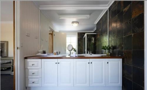 un bagno bianco con due lavandini e uno specchio di Paradise Holiday Home a Melbourne