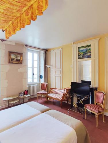 a bedroom with two beds and a television and chairs at Chambres d'hôtes du domaine de l'Isle in Civray-de-Touraine