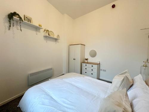 a bedroom with a large white bed and a dresser at City Haven - Modern 2 Bedroom in Sheffield in Sheffield