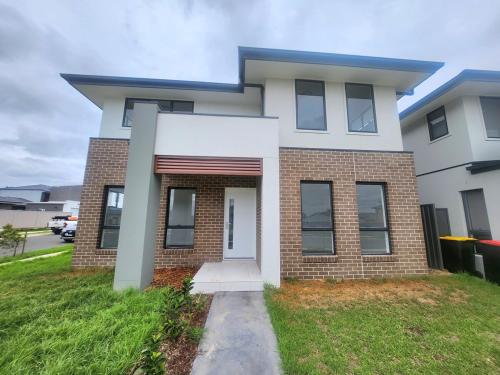 a white and red brick house with a driveway at New, Spacious and Cozy Home at Austral in Austral