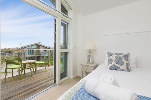 a bedroom with a bed and a balcony with a table at 64 Una in Carbis Bay