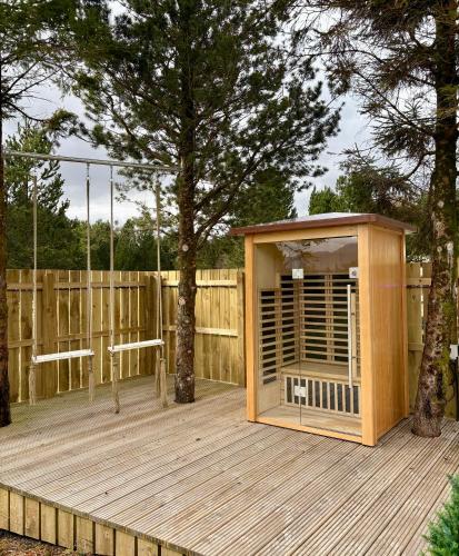 a wooden cabin on a wooden deck with a tree at Mingarry Park in Acharacle