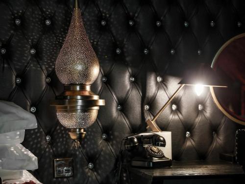a lamp on a table next to a telephone at Crazy Bear Stadhampton in Stadhampton