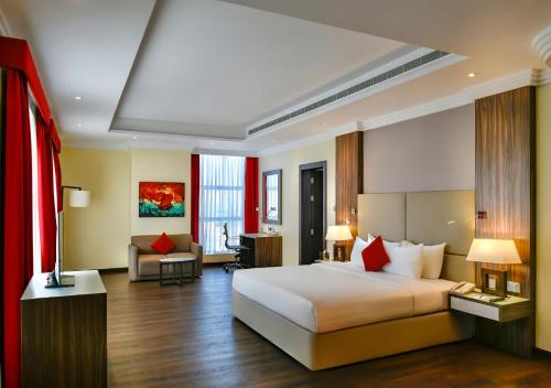 a bedroom with a large bed and a living room at Swiss-Belhotel Seef Bahrain in Manama