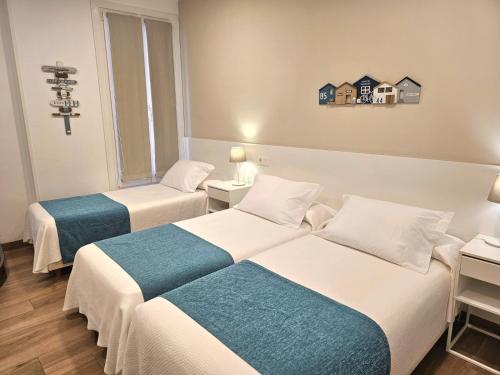 a hotel room with two beds and a cross on the wall at Pensión Txiki Polit in Zarautz