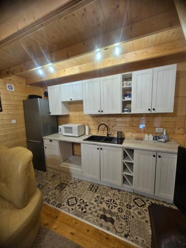a kitchen with white cabinets and a sink and a refrigerator at Rentyny Rodzinny dom wypoczynkowy nad jeziorem in Rentyny