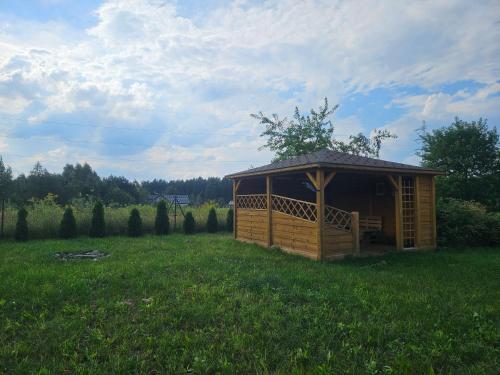 a wooden cabin in the middle of a grass field at Rentyny Rodzinny dom wypoczynkowy nad jeziorem in Rentyny