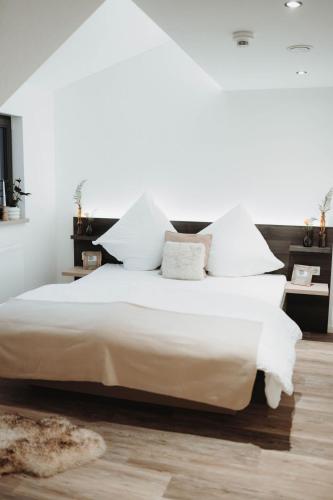 a bedroom with a large white bed with white pillows at Häserhof Gästehaus & Stall-Loft in Raddestorf