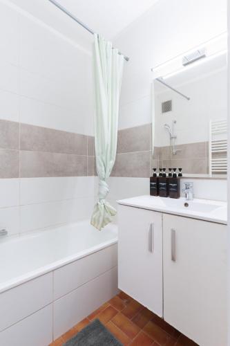 une salle de bain blanche avec une baignoire et un lavabo dans l'établissement Le Cali, Terrase, Parking, Piscine, Clim, à Villeneuve-Loubet