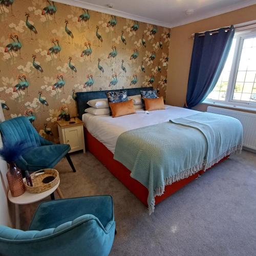 a bedroom with a bed and a chair in it at Saltmarsh Rooms at Armeria in Wells next the Sea in Wells next the Sea