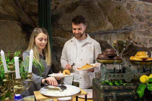 Um homem e uma mulher numa cozinha a preparar comida. em Abadía Caldaria em Arnoia