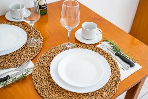 a wooden table with white plates and wine glasses at Iliada Studios in Karpathos Town