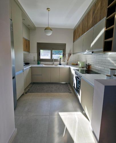 a large kitchen with white appliances and a window at The little house in Kaiafas in Sidhirodhromikós Stathmós Zakháros