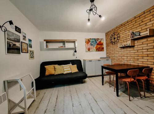 a living room with a black couch and a table at Cudnie tu - Borsk in Borsk