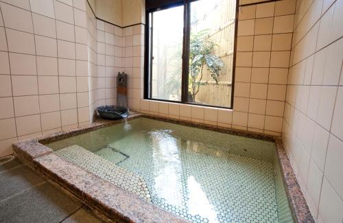 a swimming pool in a bathroom with a window at Hinodeya in Ito