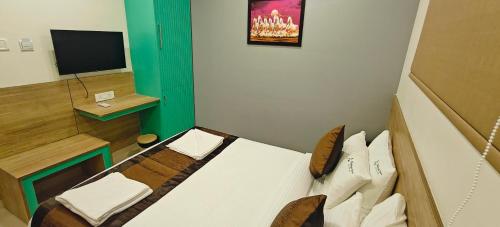 a small room with a bed and a television at Akshays Inn in Chengalpattu