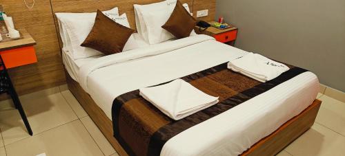 a large bed with white sheets and brown pillows at Akshays Inn in Chengalpattu