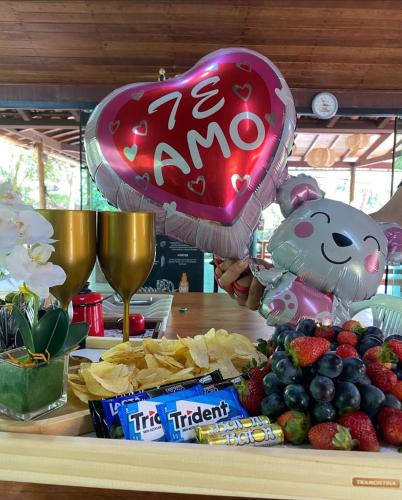 a person holding a heart balloon next to a table with fruit at Chalés Riacho da Serra Capitólio in Guapé