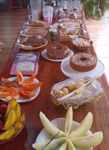 a long table filled with plates of food and fruit at Chalés Riacho da Serra Capitólio in Guapé