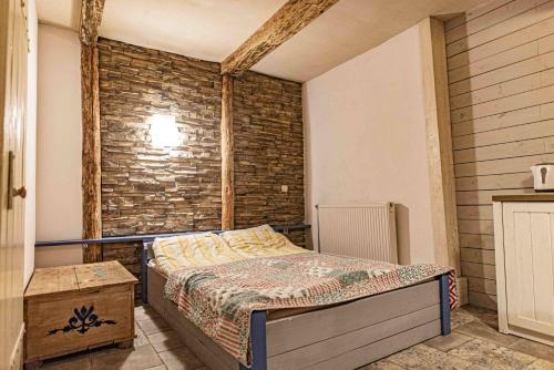 a bedroom with a bed and a brick wall at Apartamenty Folwark Malinowy Chruśniak in Bisztynek