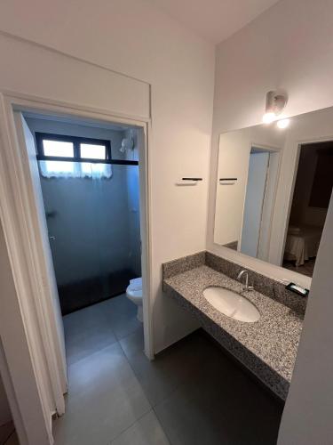 a bathroom with a sink and a toilet and a mirror at Hotel Nações Plaza in Bauru