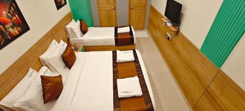 a room with two beds and a television at Akshays Inn in Chengalpattu
