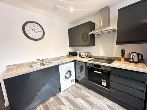 a kitchen with a washing machine and a clock on the wall at The Railway Apartments Darlington in Darlington
