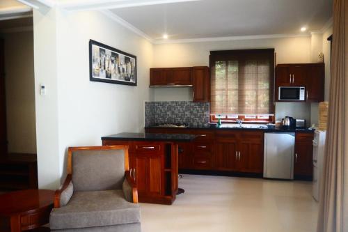 a kitchen with wooden cabinets and a chair in it at The Gecho Inn Country in Jepara