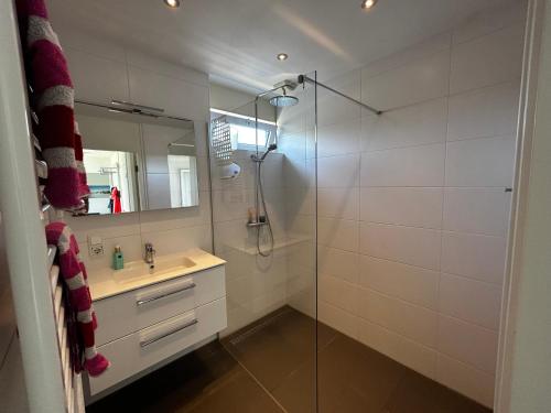 ユリアーナドルプにあるBungalow Noordzee Dのガラスのシャワーと洗面台を備えたバスルーム