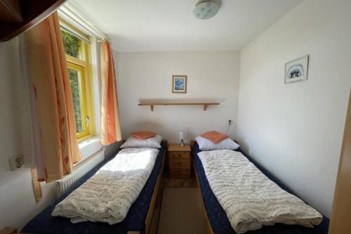 two beds in a room with a window at Albatros 327 in Julianadorp