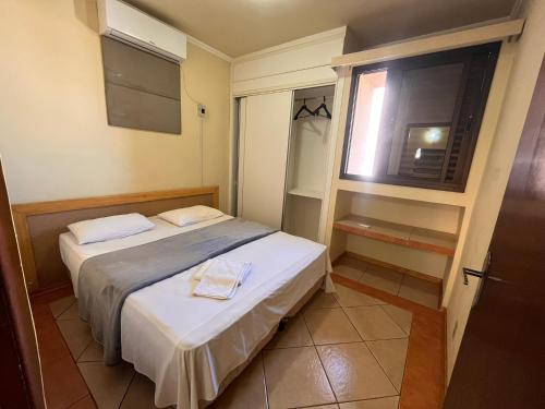 a small bedroom with two beds and a window at Hotel Nações Plaza in Bauru