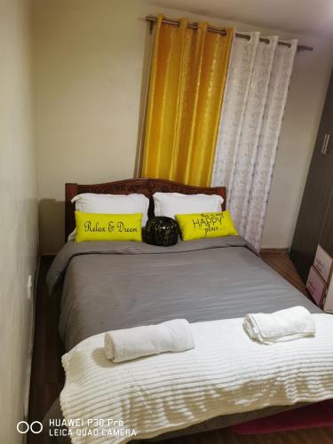 a bedroom with a bed with yellow and white pillows at Micasa Homes BnB 5 in Limuru