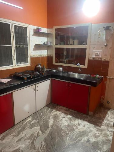 a kitchen with red and white cabinets and a sink at Vatsalya Homestay Kumbhashi in Kōtatattu