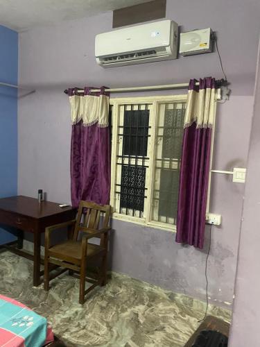 a room with a table and a window with purple curtains at Vatsalya Homestay Kumbhashi in Kōtatattu