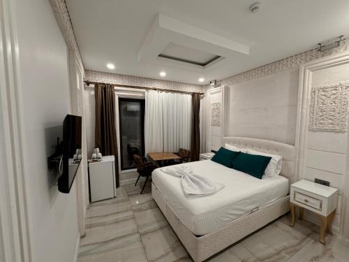 a white bedroom with a bed and a desk at Midyat Amaara Konağı Otel&Cafe in Midyat