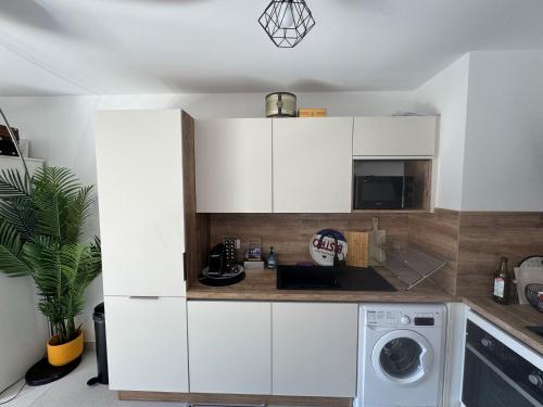 une cuisine avec des armoires blanches et une machine à laver dans l'établissement Superbe 3 pièces familiale, à Menton