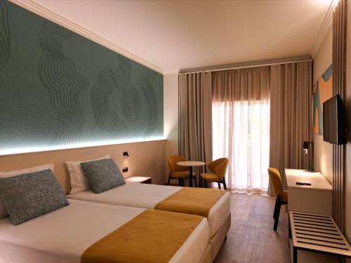 a hotel room with a bed and a window at Ukino Palmeiras Village - 24h All Inclusive in Armação de Pêra