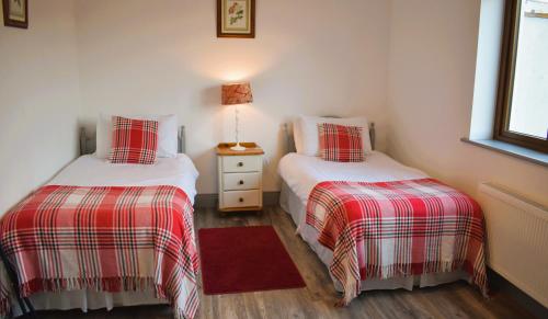 two beds in a room with a red and white blanket at Doolin Heights Apartment in Doolin