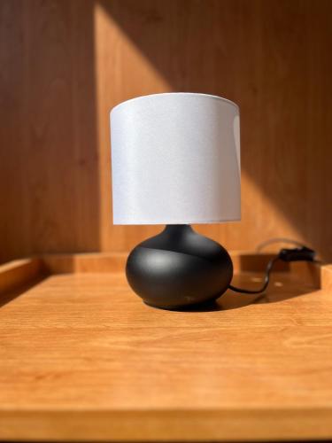 a black lamp on a table with a white shade at Hegyalja Fogadó in Sárospatak