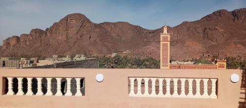 a building with a clock tower in front of a mountain at Auberge Restaurant TISSILI " Oasis de Fint" in Fint