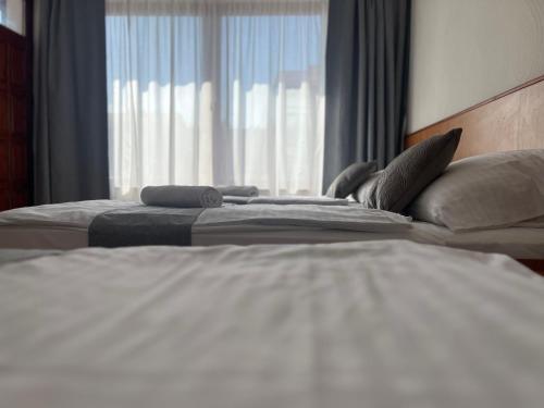 two beds in a hotel room with a window at Hegyalja Fogadó in Sárospatak