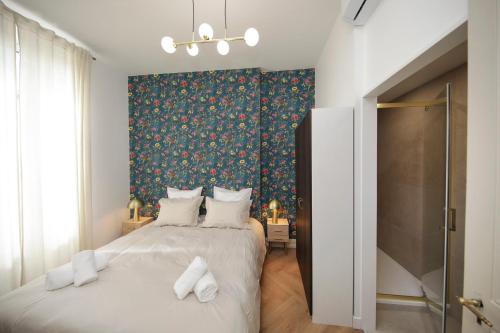 a bedroom with two beds and a floral wallpaper at LE LYNX HAUSSMANIEN appartement tout confort, climatisé avec parking privé, à deux pas du centre in Colmar