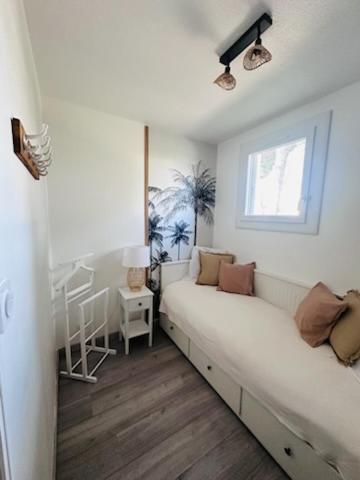 une chambre blanche avec un lit et une fenêtre dans l'établissement Appartement 2 chambres cosy, à La Grande Motte